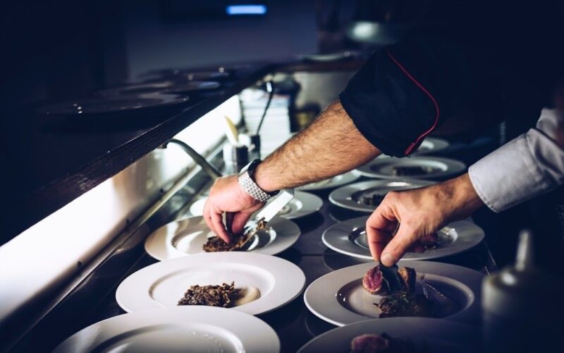 Deux cuisiniers dressent des portions soignées dans des assiettes